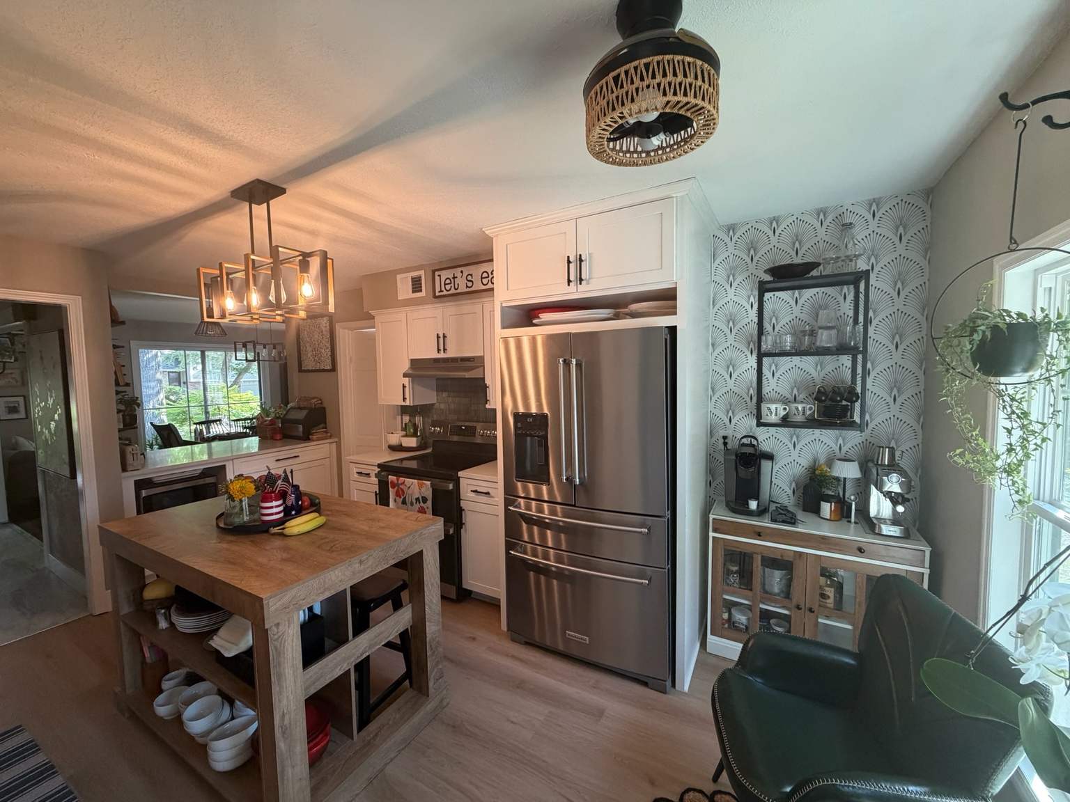 Completed kitchen with white shaker cabinetry, wood-top island, stainless refrigerator and a built-in coffee area in the former sliding-door opening