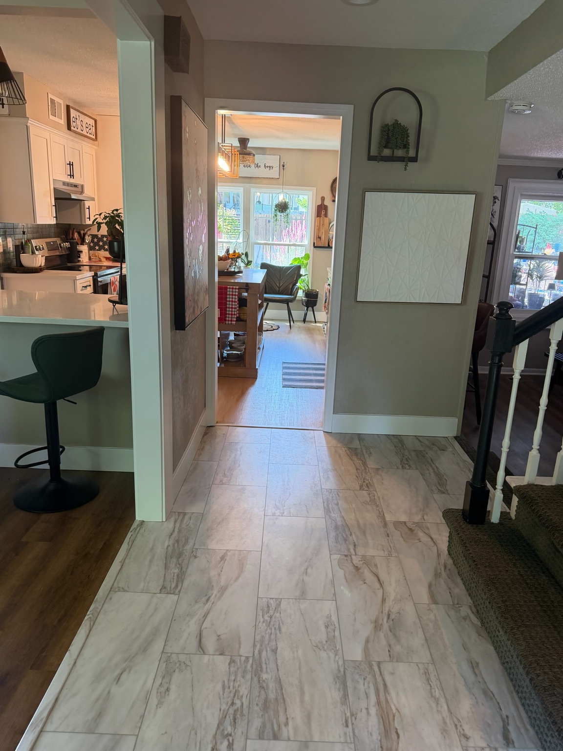 Completed entry hall with new tile floor looking through the squared-off openings into the kitchen and dining area