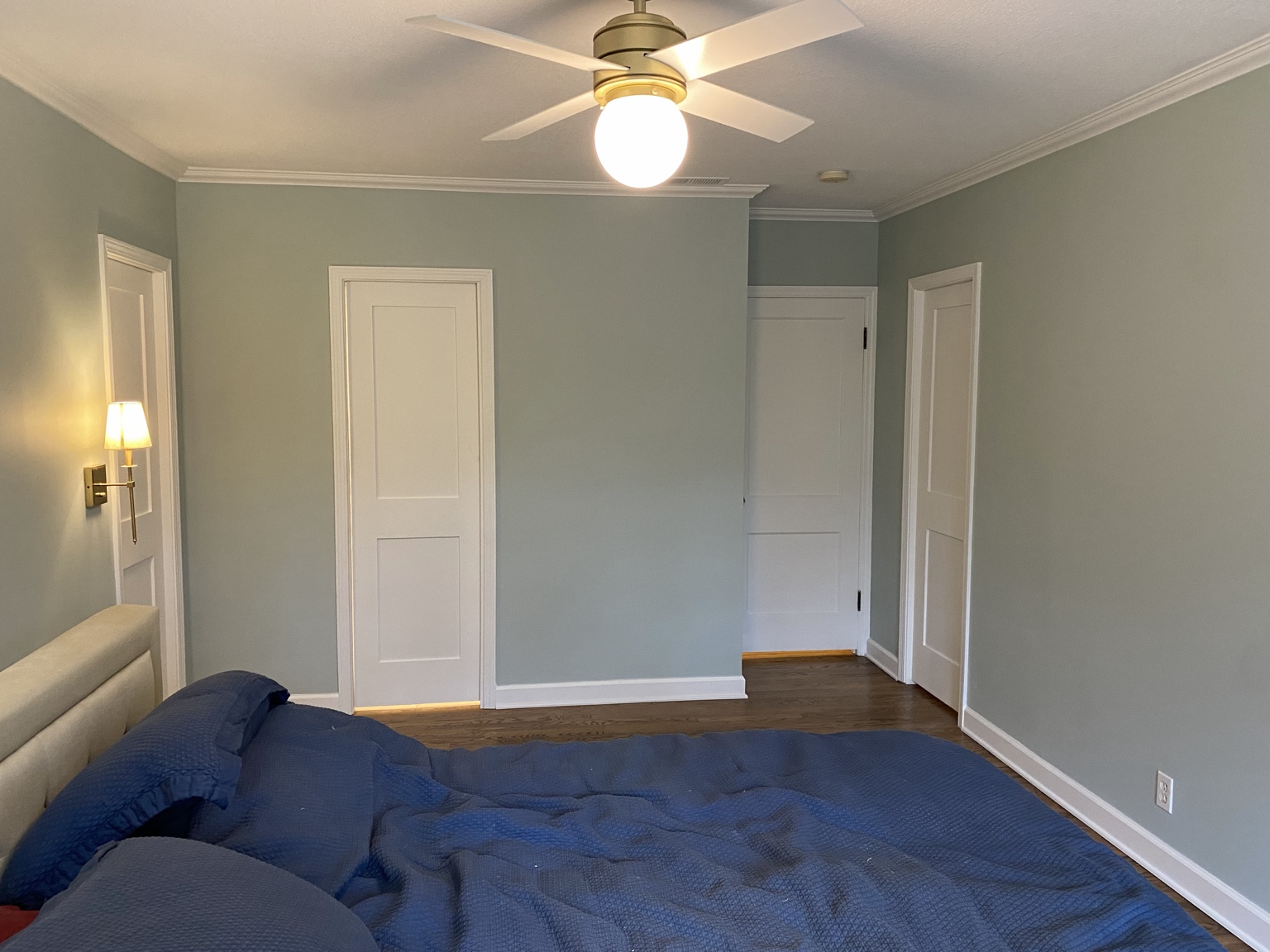The adjoining bedroom after the work, with sage-green walls, white trim, hardwood flooring and the new doorways along the reworked wall