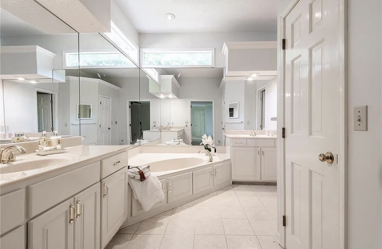 Primary bathroom before the remodel, with mirrored walls and a corner tub