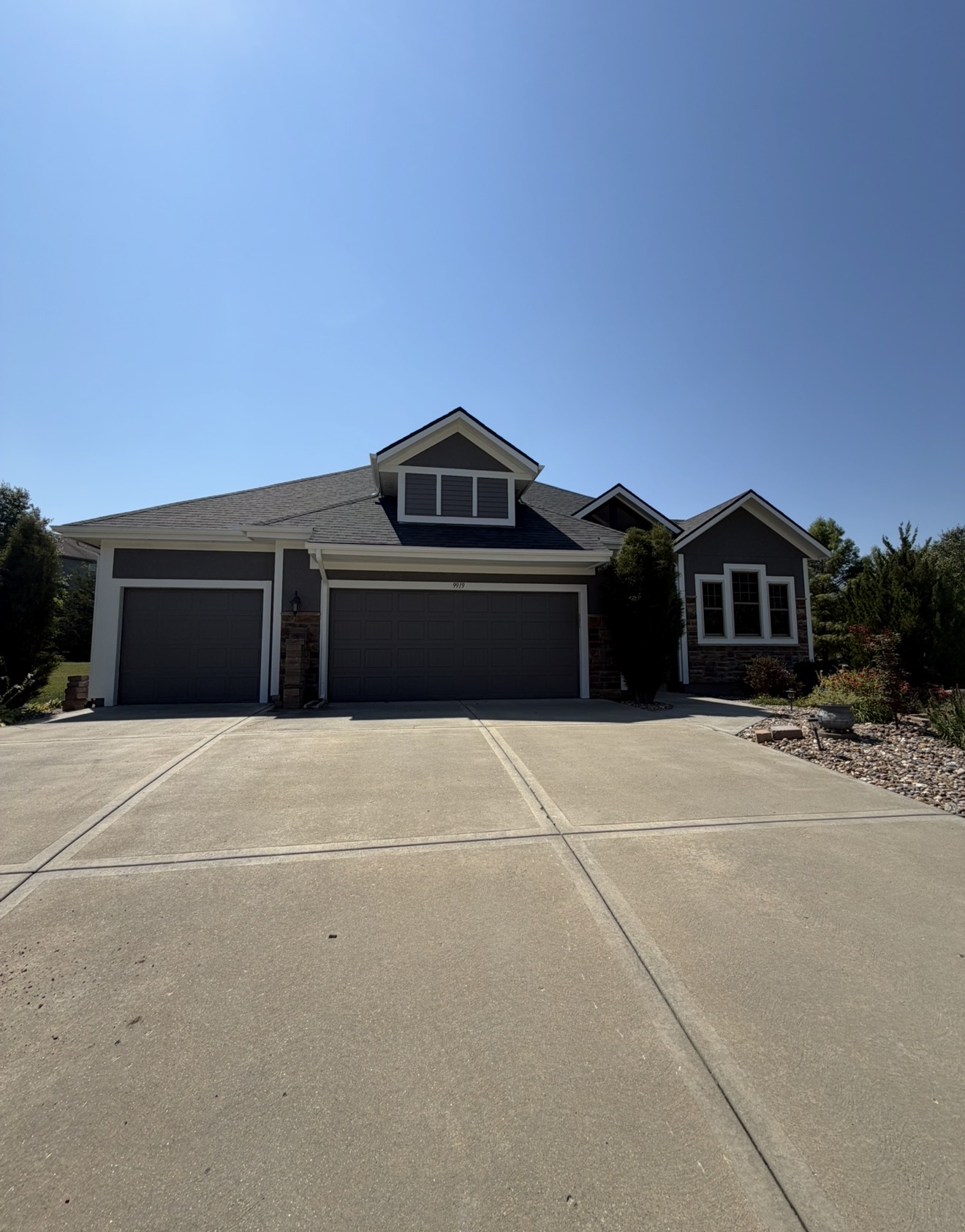 Completed front elevation repainted deep charcoal with crisp white trim, dark garage doors and stone accents