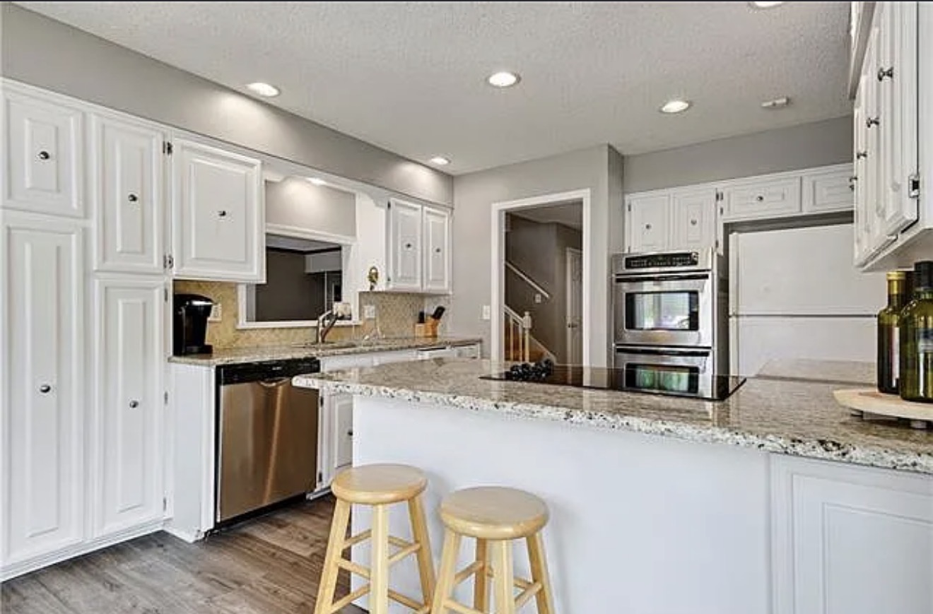 Original kitchen before the remodel with raised-panel white cabinets, granite counters and a peninsula