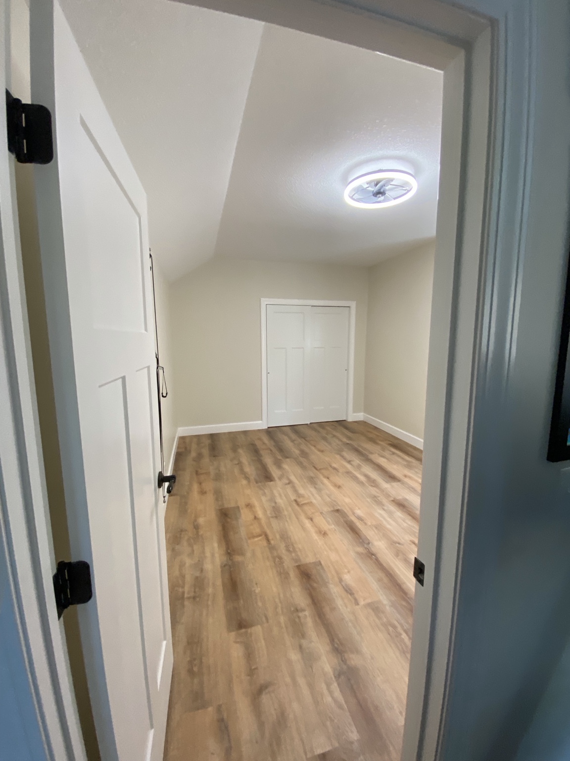 Completed room viewed from the doorway, with white door casing and wood-look flooring running through