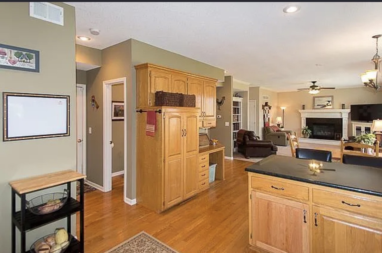 Original kitchen looking toward the living room, with a full-height oak cabinet bulkhead and walls dividing the two rooms
