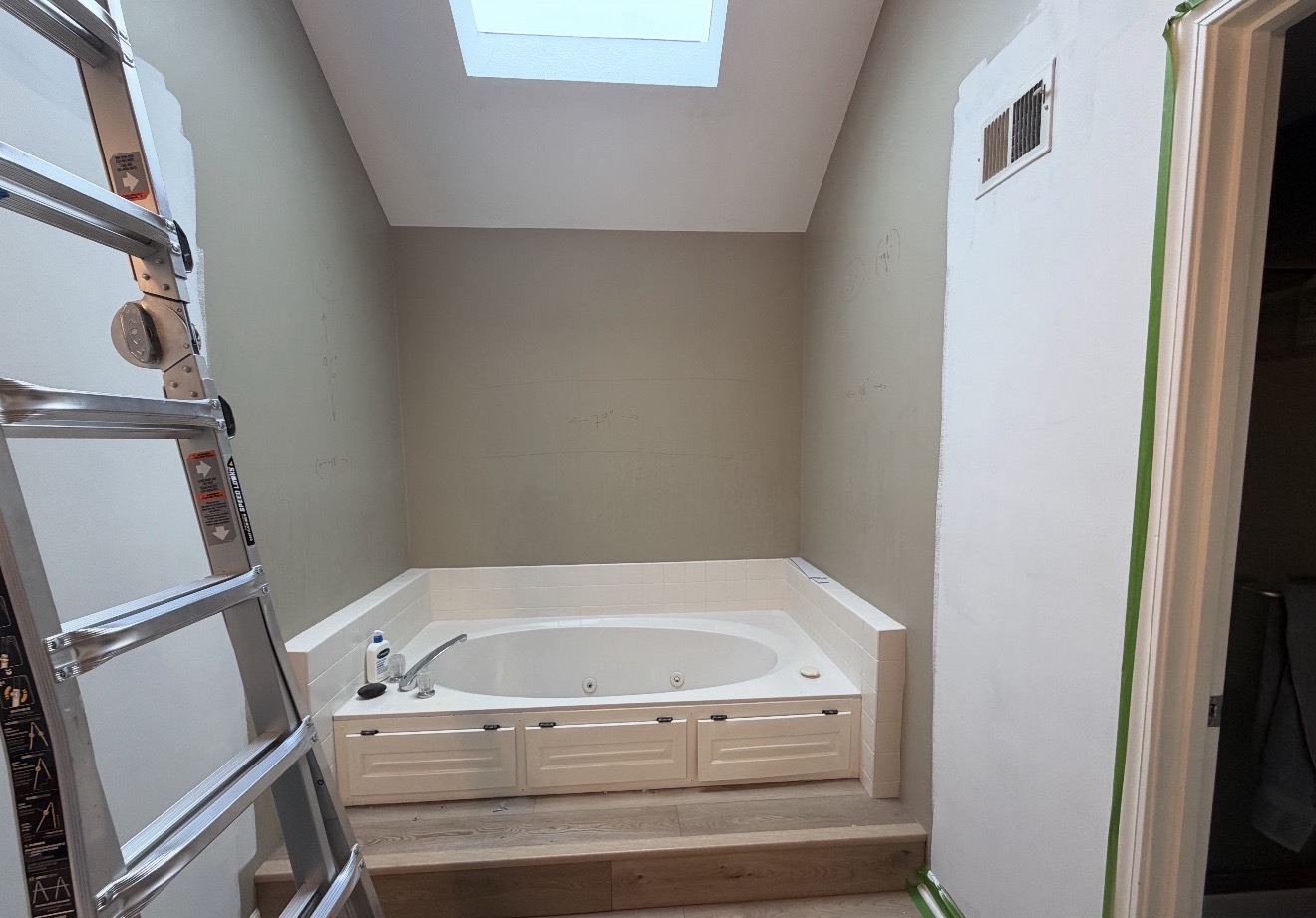 Original raised platform jetted tub set into a step-up surround beneath the skylight