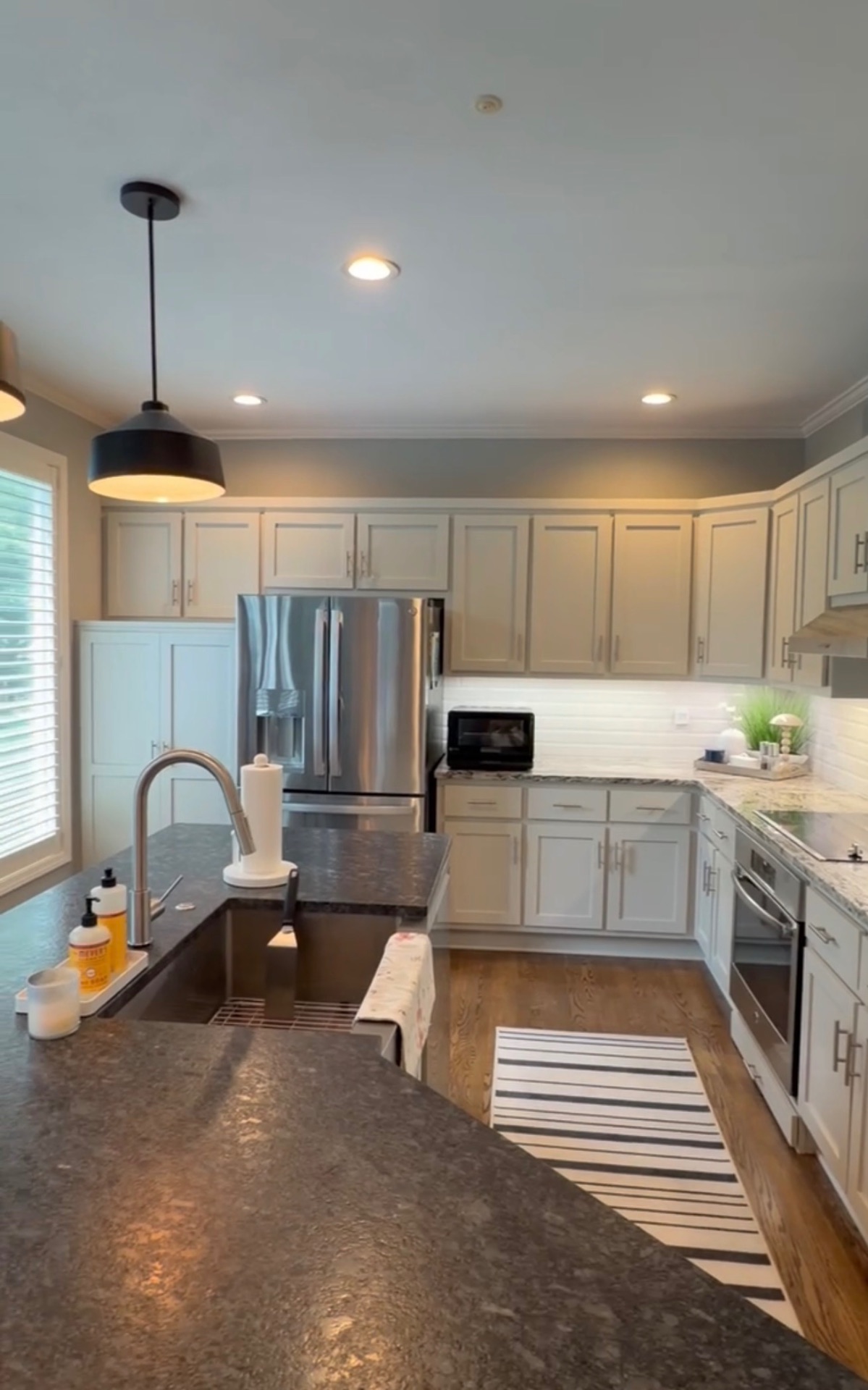 Kitchen after refinishing, with the cabinetry in a light finish seen across the island toward the refrigerator wall