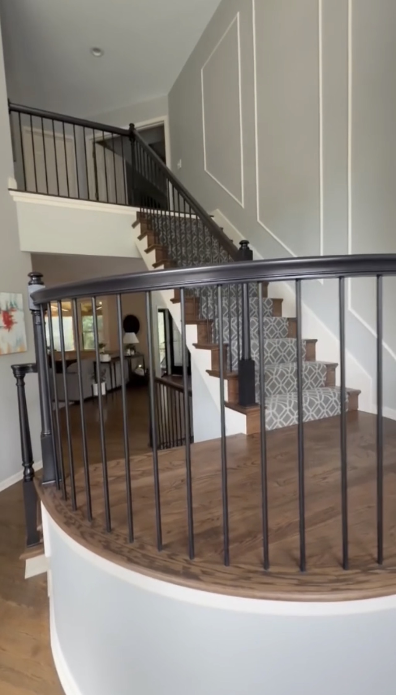 Completed staircase with repainted railing, new balusters, wood along the stair sides, a patterned carpet runner and a custom curved wood landing
