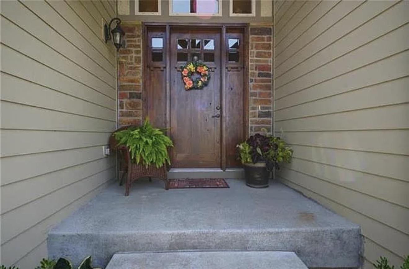 Original front entry before work, with pale green lap siding, brick columns and an unstained wood front door