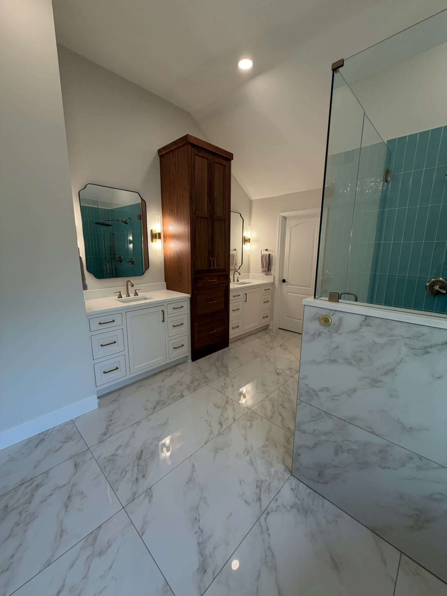 Completed bathroom view showing both vanities, the walnut storage tower and the teal-tile glass shower at right