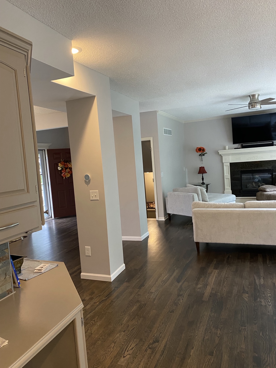 Completed view from the kitchen through the new opening to the living room and fireplace, with dark hardwood flooring throughout