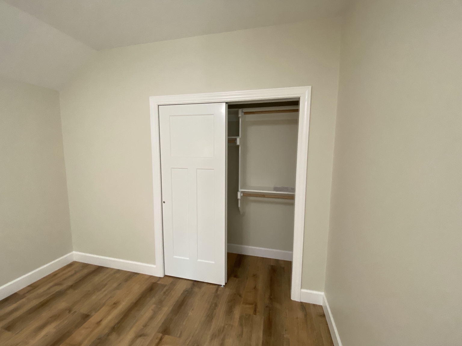 Completed closet with white bypass doors, trimmed opening and hanging rods with shelving inside