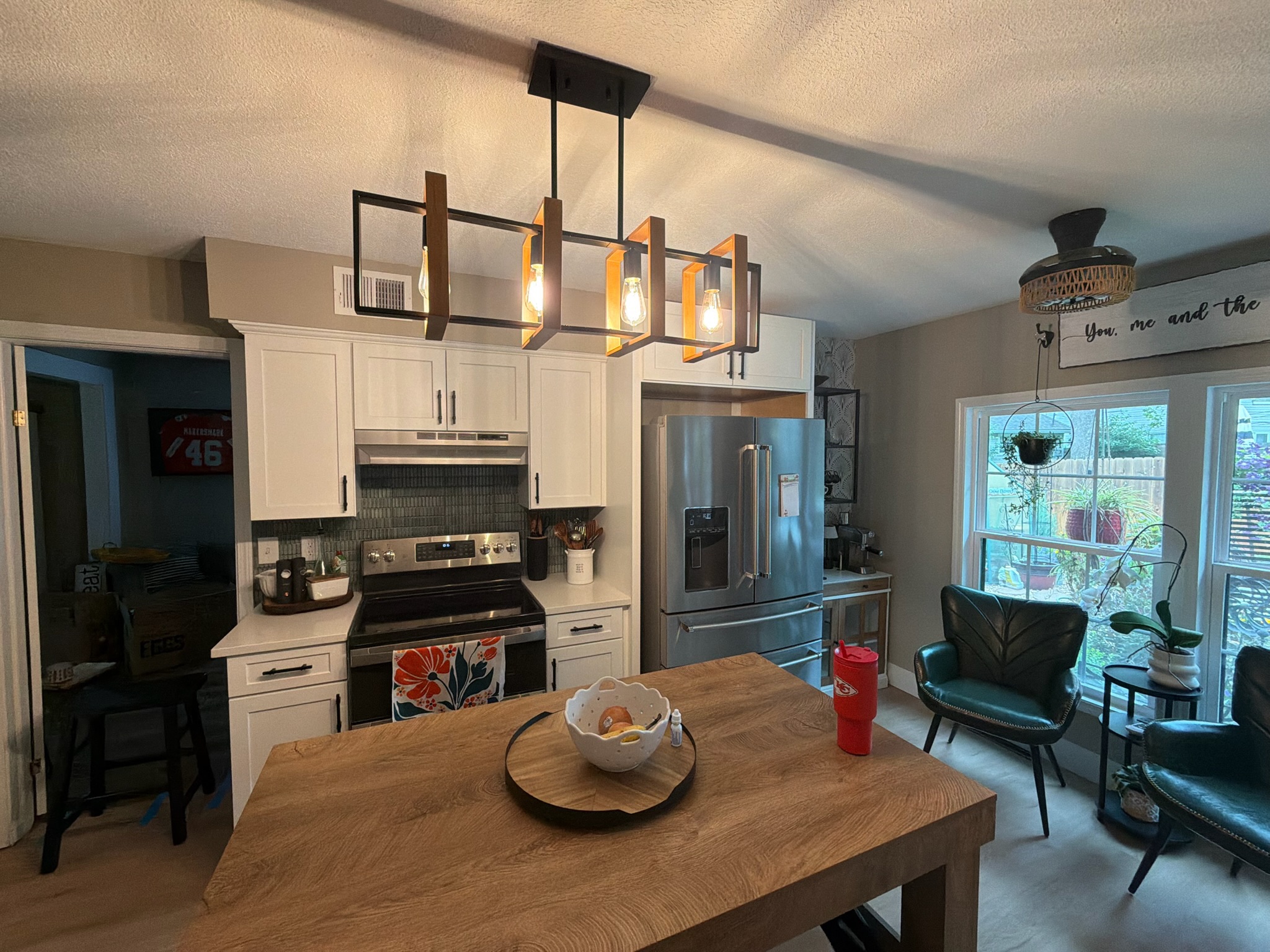 Completed range wall with white cabinetry, green tile backsplash and a linear pendant over the island