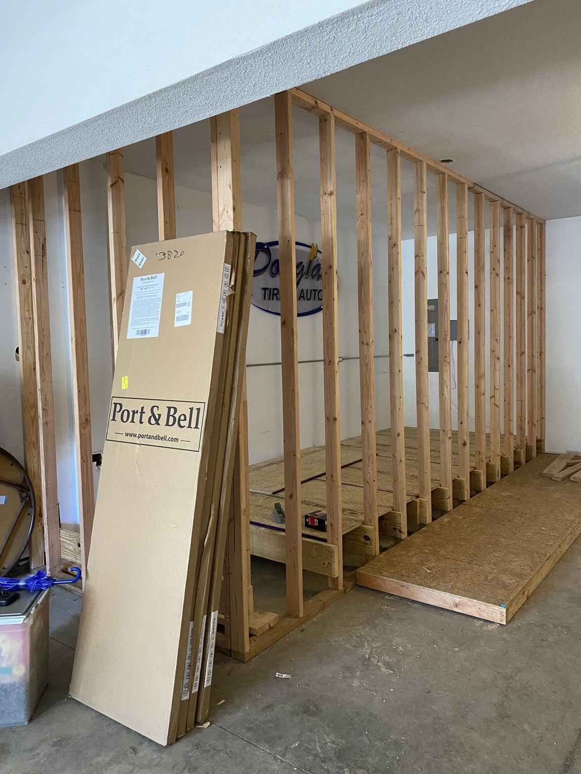 New stud framing for the walk-in closet built into the garage area, with a subfloor laid and door packages leaning against the wall