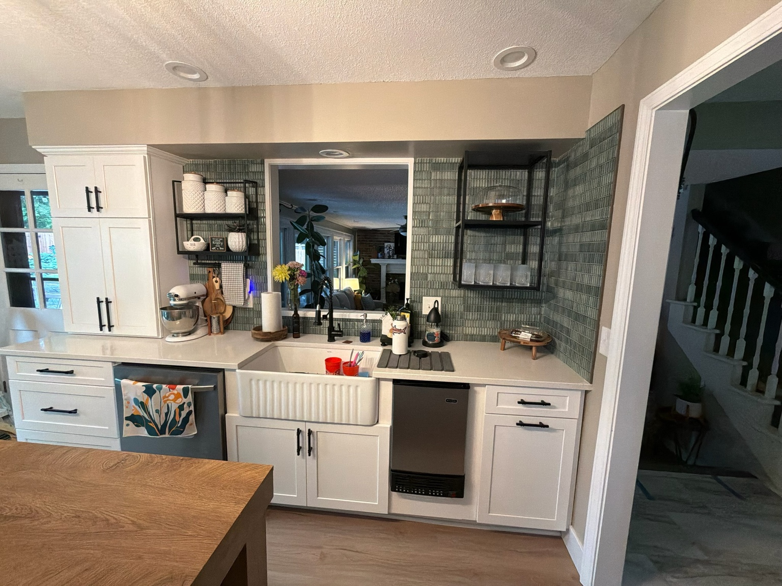 Completed sink run with farmhouse sink, green tile backsplash and open shelving